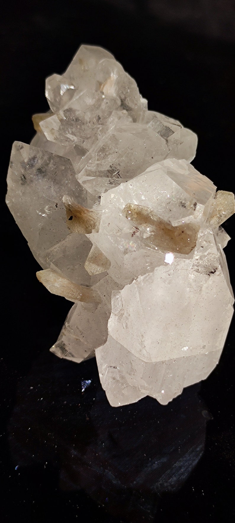 May include: A cluster of clear quartz crystals with a milky white hue. The crystals are arranged in a cluster, with some of the crystals pointing upwards and others pointing downwards. The crystals are translucent and have a slight sparkle.