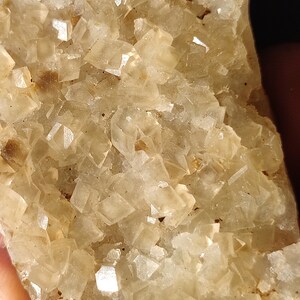 Pu&ograve; includere: Un ammasso di cristalli traslucidi di colore marrone chiaro con una texture ruvida e naturale. I cristalli sono raggruppati in una formazione densa, creando un pezzo visivamente interessante e unico.