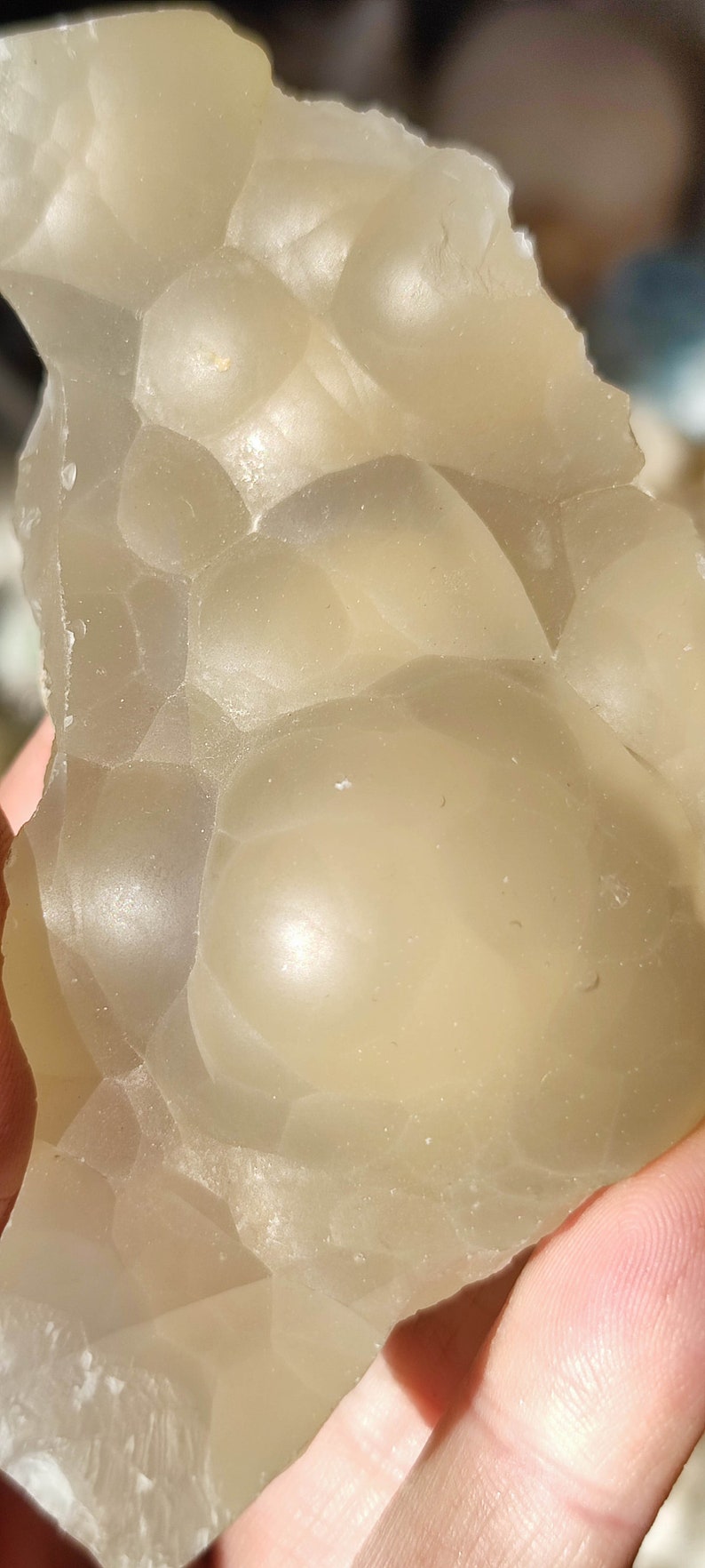 K&ouml;nnte beinhalten: Nahaufnahme eines hellbeigen, durchscheinenden, unregelm&auml;&szlig;ig geformten Steins mit einer glatten, abgerundeten Oberfl&auml;che. Der Stein hat eine einzigartige, blasenartige Textur.