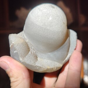 Peut inclure: Une g&eacute;ode d'agate blanche avec une surface lisse et arrondie et une base rugueuse et textur&eacute;e.