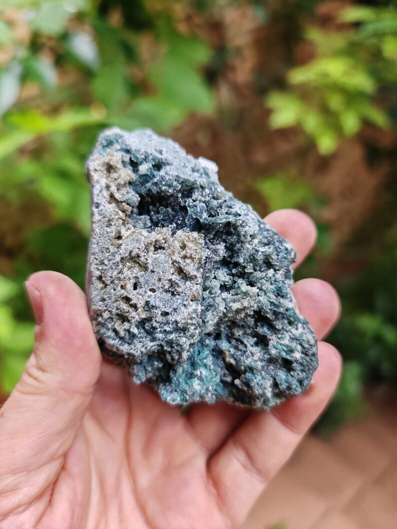 May include: A rough, green and grey rock with a crystalline texture. The rock has a natural, earthy look.