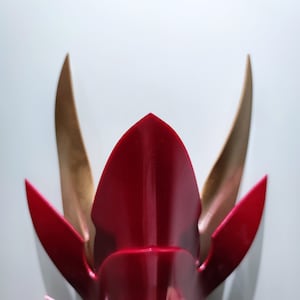 以下が含まれることがあります： 角のある赤と金の侍の兜。兜はプラスチック製で光沢のある仕上げです。