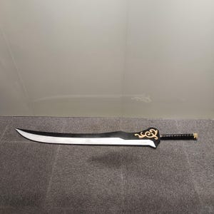 Può includere: Una spada nera e argentata con un design dorato sull'impugnatura. La spada ha una lama curva e un'impugnatura nera.