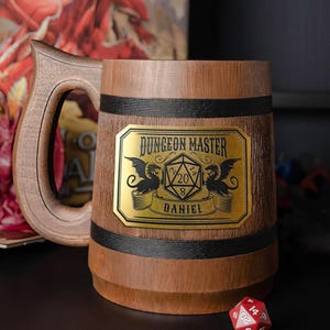 May include: A wooden beer mug with a large handle and a decorative brass plate. The plate reads "Dungeon Master" with a dragon emblem and the name "Daniel". The mug is brown with black bands.