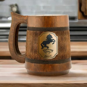 May include: A brown wooden beer stein with a black silhouette of a horse and the text "Prancing Pony Daniel" on a gold label.