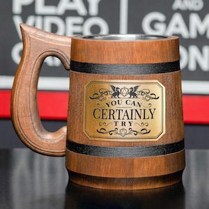 May include: A wooden beer stein with a black handle and a gold metal plaque that reads "You Can Certainly Try". The plaque has a black and white illustration of a dragon and a dice.