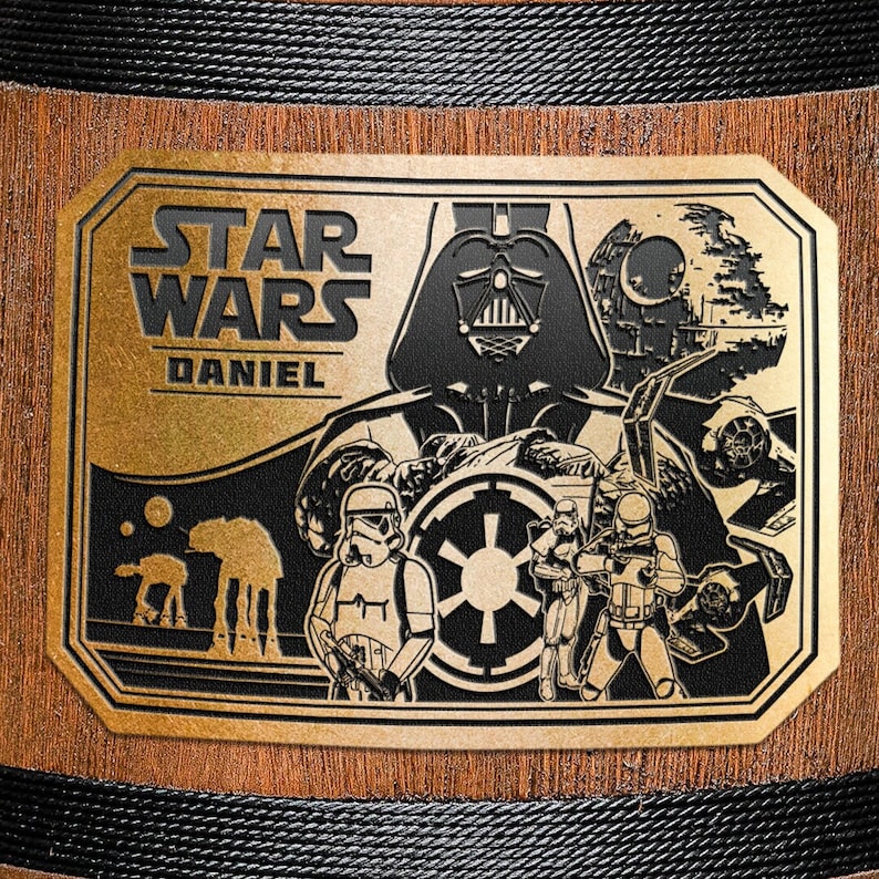 May include: A gold-colored metal plaque with a black and white image of Darth Vader and other Star Wars characters. The plaque has the text "STAR WARS DANIEL" on it.