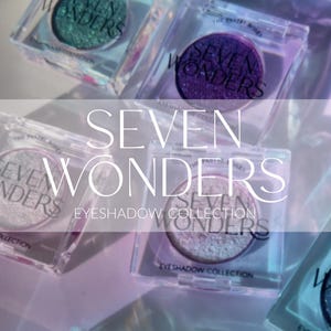 Può includere: Collezione di ombretti Seven Wonders con sei ombretti singoli in contenitori di plastica trasparente. Gli ombretti sono in tonalità di viola, verde, bianco e argento. Il testo "Seven Wonders Eyeshadow Collection" è stampato sui contenitori.