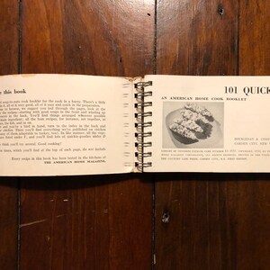 K&ouml;nnte beinhalten: Ein offenes Kochbuch mit dem Titel "101 Quickies: Ein amerikanisches Kochbuch f&uuml;r zu Hause" von Doubleday & Company, Inc. Das Buch ist mit einer Spiralbindung gebunden und zeigt auf dem Cover ein Schwarzwei&szlig;foto eines Gerichts.