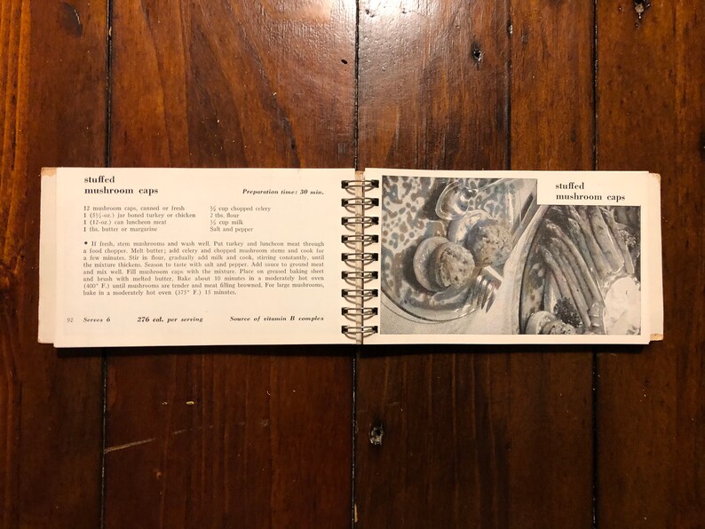 K&ouml;nnte beinhalten: Eine Seite aus einem alten Kochbuch mit einem Rezept f&uuml;r gef&uuml;llte Champignonkappen. Das Rezept enth&auml;lt Zutaten wie Champignons, Sellerie, Mehl, Milch und Truthahn- oder H&uuml;hnerfleisch. Die Seite enth&auml;lt auch ein Foto des fertigen Gerichts.