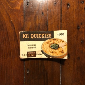 K&ouml;nnte beinhalten: Ein Vintage-Kochbuch mit dem Titel "101 Quickies" mit einem Foto einer Auflaufform auf dem Cover. Das Kochbuch kostet 1,00 $ und enth&auml;lt den Text "Jedes Rezept illustriert!" und "Getestete amerikanische Hausrezepte".
