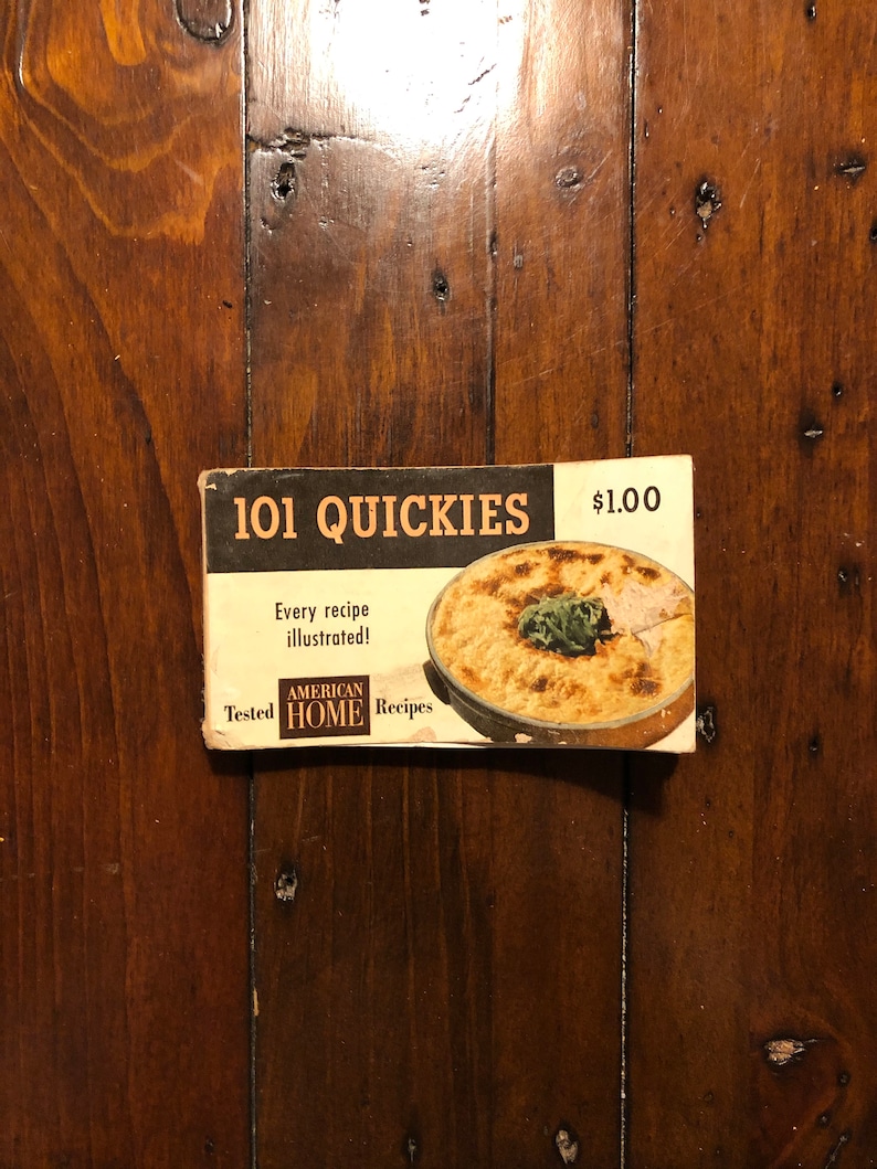 K&ouml;nnte beinhalten: Ein Vintage-Kochbuch mit dem Titel "101 Quickies" mit einem Foto einer Auflaufform auf dem Cover. Das Kochbuch kostet 1,00 $ und enth&auml;lt den Text "Jedes Rezept illustriert!" und "Getestete amerikanische Hausrezepte".