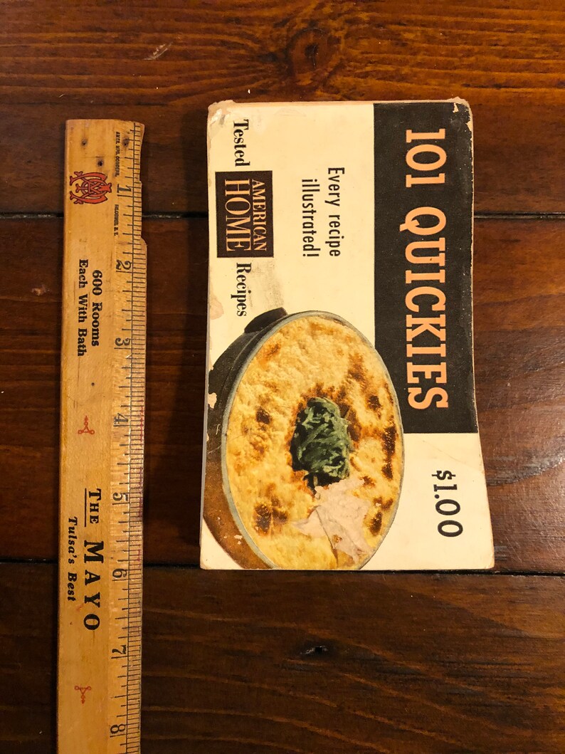 K&ouml;nnte beinhalten: Ein Vintage-Kochbuch mit dem Titel "101 Quickies" zum Preis von 1,00 $. Der Umschlag zeigt ein Foto einer Auflaufform mit gr&uuml;nem Garnierung und dem Text "American Home Recipes" und "Every recipe illustrated!"