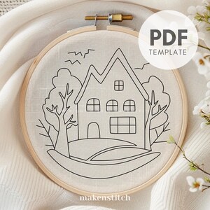 May include: A black and white line drawing of a house with two trees and birds in the sky. The drawing is on a piece of fabric in a wooden embroidery hoop. The text "PDF TEMPLATE" is in the upper right corner of the image.