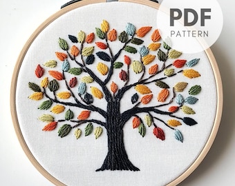 May include: Embroidered tree design on white fabric, set in a wooden hoop. The tree trunk and branches are black, with colorful leaves in shades of orange, yellow, green, and blue. The text "PDF PATTERN" is visible.