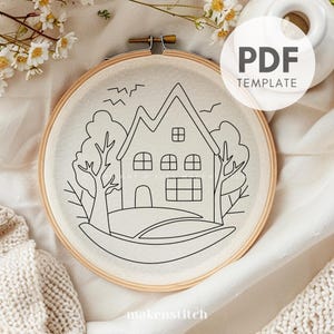 May include: Black and white line art embroidery pattern of a house with two trees and a grassy hill. The pattern is on a white fabric in a wooden embroidery hoop. The text "PDF TEMPLATE" is in the upper right corner of the image.