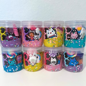 Dollhouse party favor playdough jars in pink, teal, purple, and yellow – the perfect kitty birthday party gift or girl birthday surprise. Each jar includes soft play dough, candy charm, acrylic gems, and cute trinkets for sensory play. Fun kids activity toy, personalized party favor, and creative dollhouse adventure keepsake