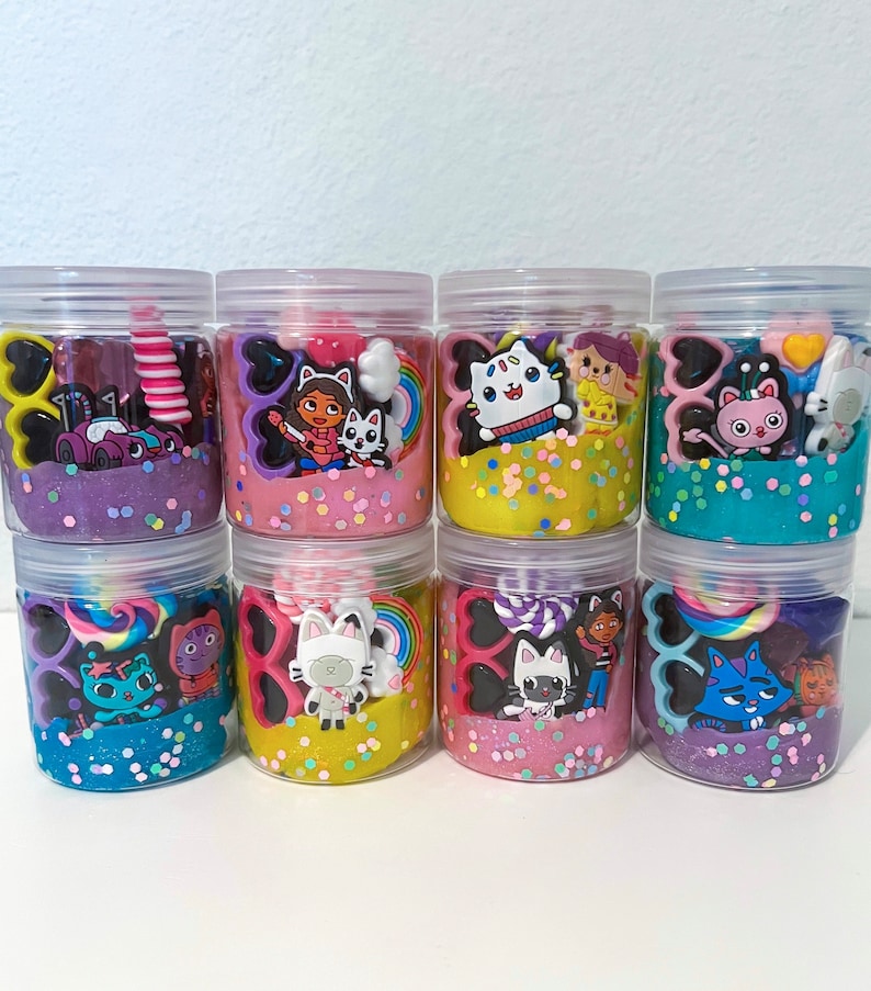 Dollhouse party favor playdough jars in pink, teal, purple, and yellow – the perfect kitty birthday party gift or girl birthday surprise. Each jar includes soft play dough, candy charm, acrylic gems, and cute trinkets for sensory play. Fun kids activity toy, personalized party favor, and creative dollhouse adventure keepsake