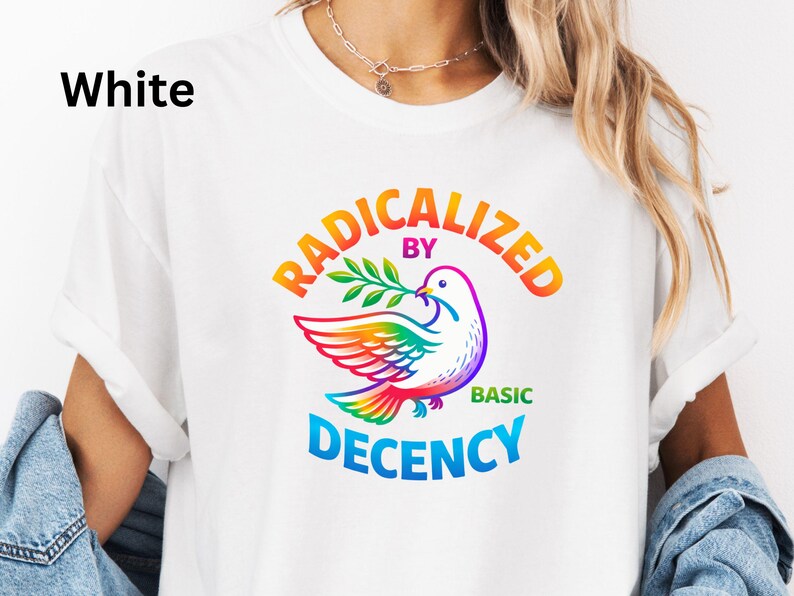 May include: White t-shirt with the text "RADICALIZED BY BASIC DECENCY" in a rainbow arc above a colorful dove holding an olive branch. The dove's wings and tail are in rainbow colors. The word "White" is in the upper left corner.