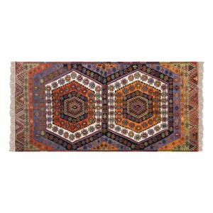 May include: A rectangular rug with a geometric pattern. The rug features a central design of two large, connected hexagons in shades of orange, black, and white. The border includes various colours like purple, green, and red. The rug has fringed edges.