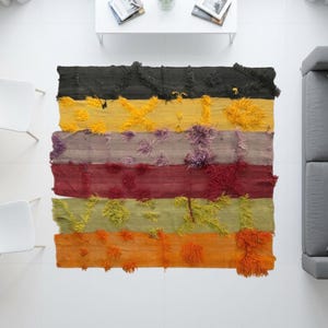 Könnte beinhalten: Ein rechteckiger Teppich mit horizontalen Streifen in Schwarz, Gelb, Violett, Rot, Grün und Orange. Der Teppich hat eine strukturierte Oberfläche mit erhabenen, zotteligen getufteten Akzenten in passenden Farben auf jedem einzelnen Streifen.