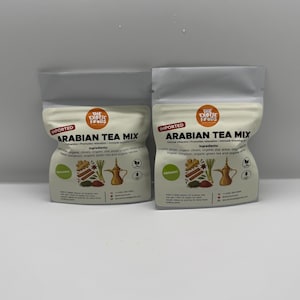 Puede incluir: Dos paquetes de "Arabian Tea Mix" con las palabras "Importado" y "Orgánico". El embalaje presenta ilustraciones de ingredientes de té y una tetera tradicional. La mezcla de té incluye clavo, anís estrellado y canela orgánicos.