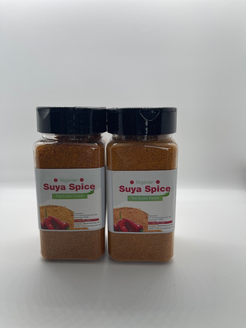 May include: Two glass jars of Nigerian Suya Spice, a blend of spices for grilling meat. The jars are labeled "Nigerian Suya Spice The Exotic Foods" and feature a red chili pepper graphic.