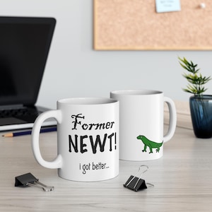 May include: White ceramic mug with black text that reads "Former Newt! I got better..." and a green cartoon lizard on the other side.