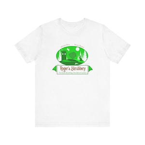 Peut inclure: T-shirt blanc avec un logo vert qui dit "Roger's Shrubbery" avec le texte "Always Nice - Never Shrewy" et "The Fine Shrubbing This Side of Camelot" en dessous.