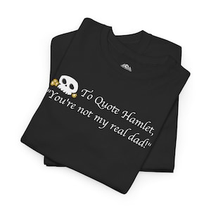 Op de afbeelding: Zwart T-shirt met een witte schedel en gekruiste beenderen afbeelding en de tekst "To Quote Hamlet, "You're not my real dad!"