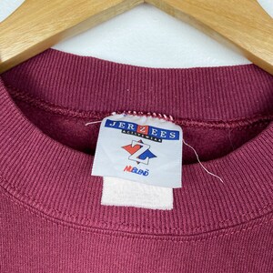 May include: A maroon sweatshirt with a Jerzees Activewear tag. The tag has a white diamond with a black Z in the center and the words "NuBlend" below it.