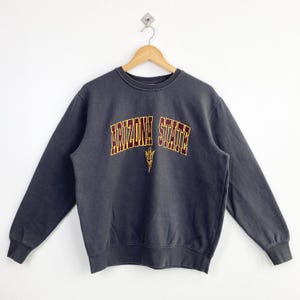 Puede incluir: Una sudadera gris oscuro con un logotipo de "Arizona State" en granate y amarillo en la parte delantera.