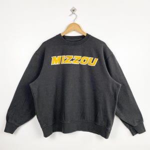 May include: A dark gray sweatshirt with a yellow embroidered logo that says "MIZZOU".