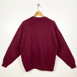 May include: A maroon sweatshirt with long sleeves and a crew neck.
