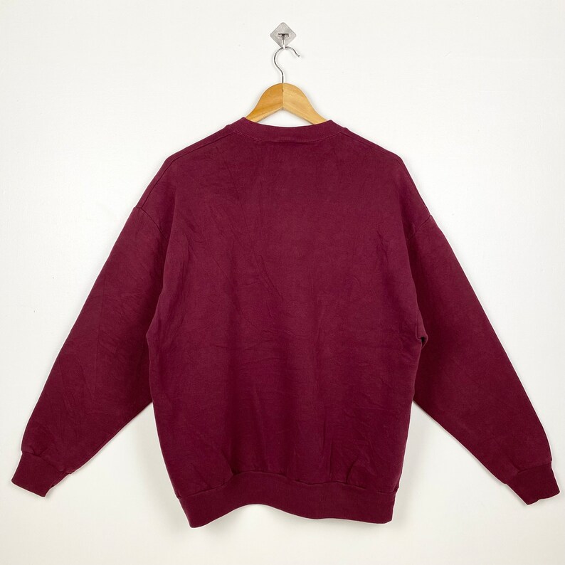 May include: A maroon sweatshirt with long sleeves and a crew neck.