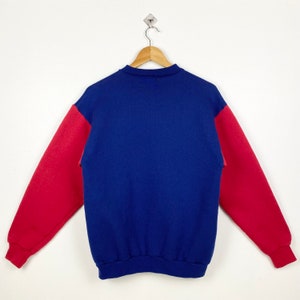 May include: A blue and red sweatshirt with long sleeves. The sleeves are red and the body of the sweatshirt is blue.