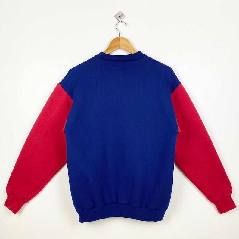 May include: A blue and red sweatshirt with long sleeves. The sleeves are red and the body of the sweatshirt is blue.