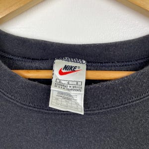 Puede incluir: Sudadera negra Nike con un logotipo blanco de Nike y una etiqueta de talla. La etiqueta dice "L G G Ensamblado en M&eacute;xico con componentes de EE. UU.".