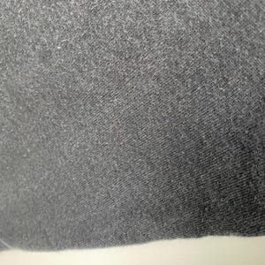 Puede incluir: Primer plano de una tela gris oscura con una superficie texturizada.