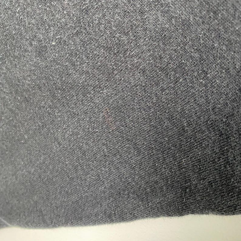 Puede incluir: Primer plano de una tela gris oscura con una superficie texturizada.