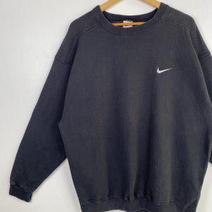 Puede incluir: Sudadera Nike negra con un logotipo Swoosh blanco en el pecho izquierdo.
