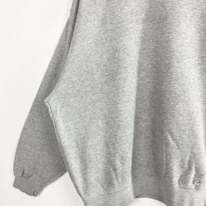 May include: A heather gray sweatshirt with a crew neck and long sleeves. The sweatshirt is made of a soft, comfortable material. The cuffs and hem are ribbed.