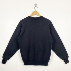 May include: A black crew neck sweatshirt with long sleeves and a ribbed hem.