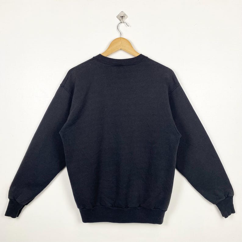 May include: A black crew neck sweatshirt with long sleeves and a ribbed hem.
