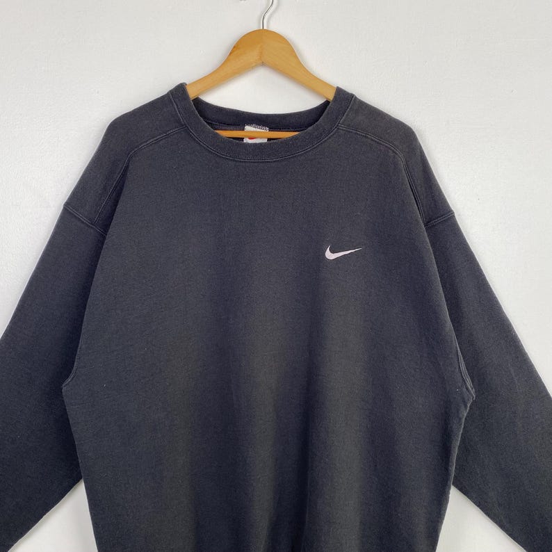 Puede incluir: Una sudadera Nike negra con un logotipo Swoosh blanco en el pecho izquierdo.