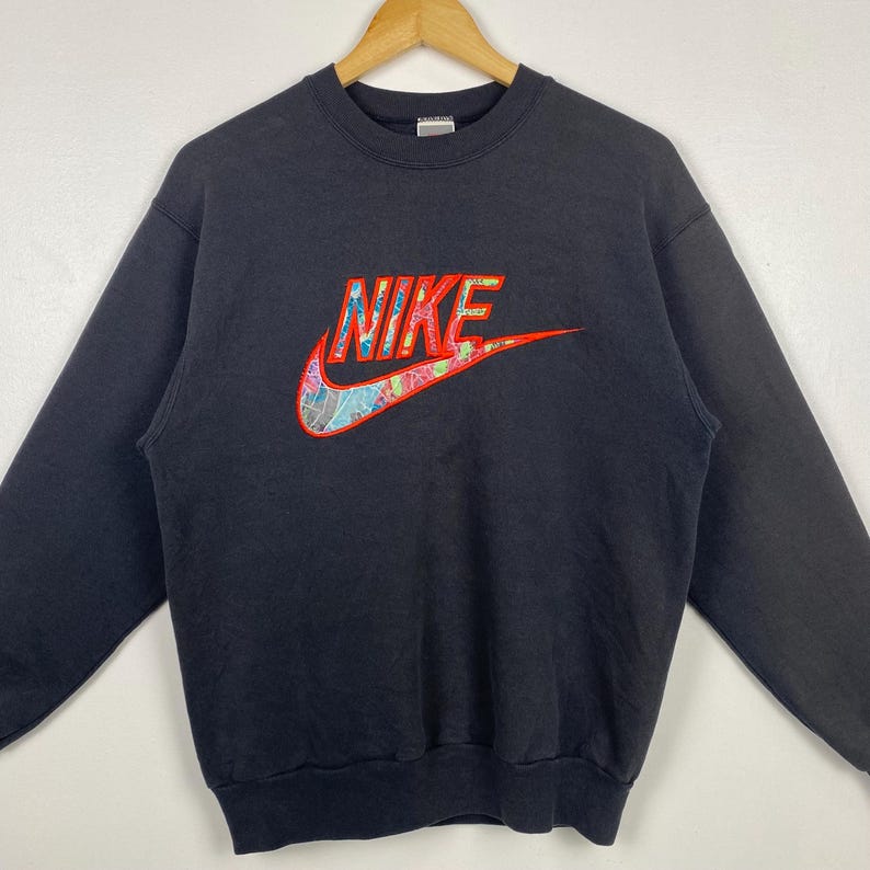 May include: Black sweatshirt with a colorful embroidered Nike logo.