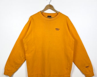 May include: A yellow sweatshirt with a small black and red logo that says "Puma" on the front. The sweatshirt has long sleeves and a crew neck.
