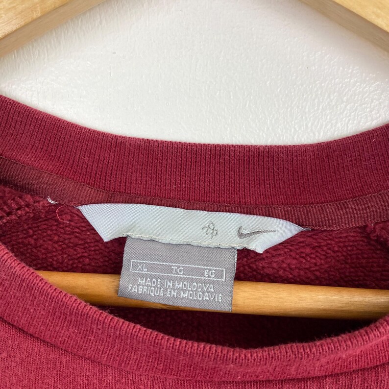 May include: A maroon sweatshirt with a white tag that reads "XL TG EG MADE IN MOLDOVA FABRIQUE EN MOLDAVIE" and a Nike logo.