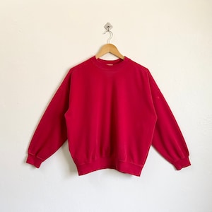 May include: A red long-sleeved sweatshirt with a crew neck.