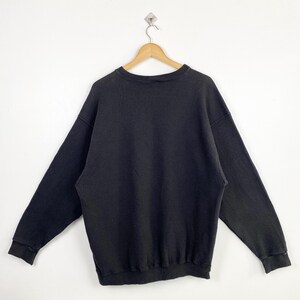 Puede incluir: Una sudadera negra de manga larga con cuello redondo.